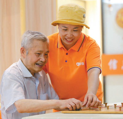 福建省福州市鼓楼区安泰街道居家社区养老服务照料中心的工作人员（右）与老人进行手指训练游戏。谢贵明摄