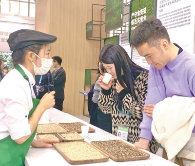 觀眾在星巴克展位品鑒雲南產咖啡豆。本報記者 施 芳攝