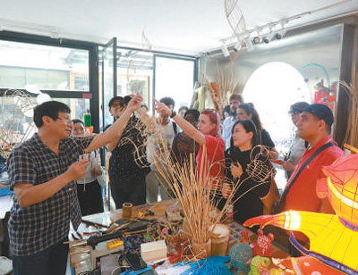 顾业亮（左一）向游客介绍展示秦淮灯彩制作。图为南京历史城区保护建设集团有限公司提供