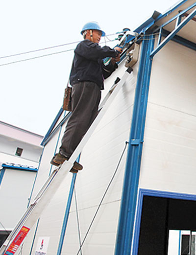 8月25日,施工工人为学校新建的活动板房安装照明,供水等附属设施.