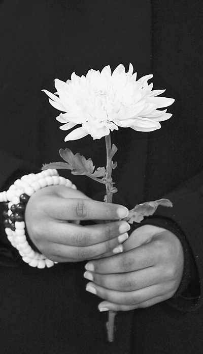 4月21日,一位藏族大学生手持菊花为玉树地震遇难同胞默哀.